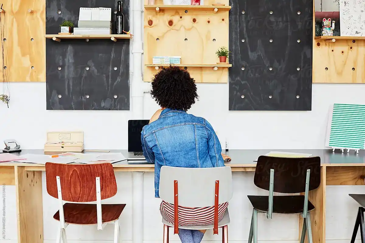 Woman seen with her back turned, working on her laptop